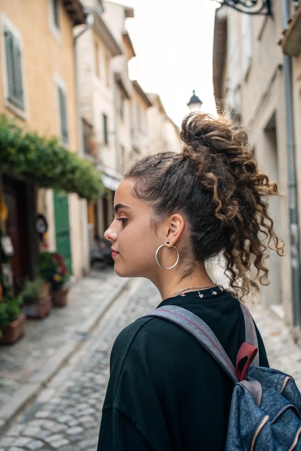 15 Easy Travel Hairstyles for Curly Hair That Save Time and Turn Heads 7 Half-Up Curly Bun with Hoop Earrings